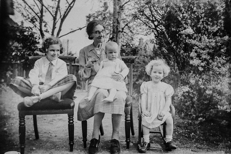 Eine alte Frau mit drei kleinen Kindern sitzt auf einer Bank. 